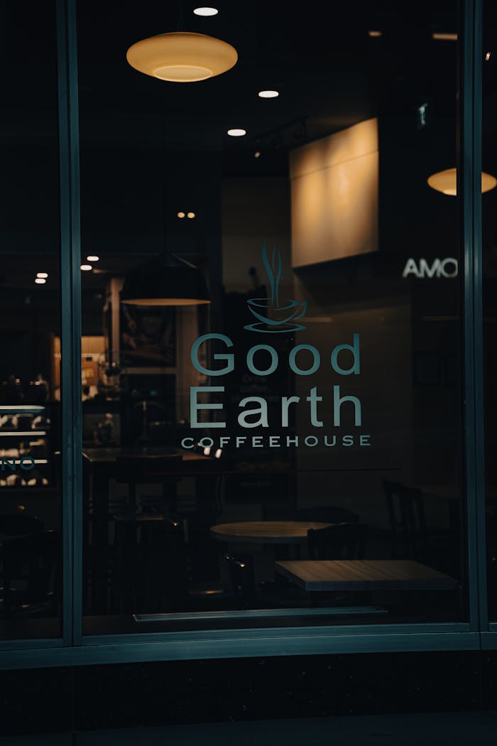 Dimly lit coffeehouse window displaying Good Earth Coffeehouse signage.